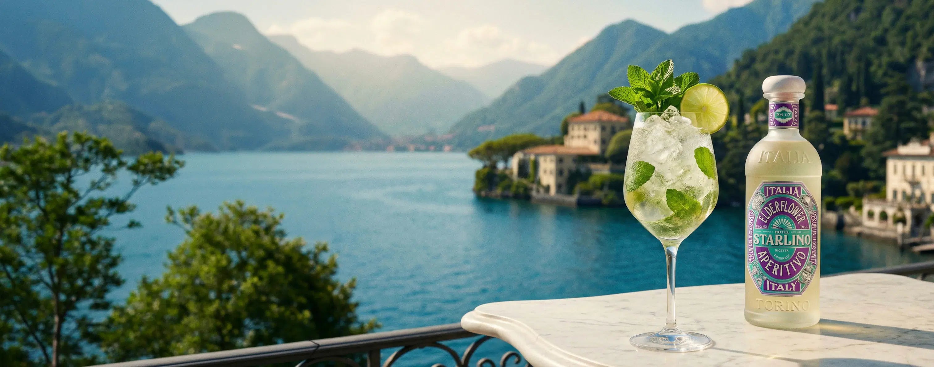 Hugo Spritz cocktail garnished with fresh mint and a lime wheel beside a bottle of Hotel Starlino Elderflower Aperitivo on a marble balcony table overlooking Lake Como